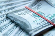 $100 bills folded with rubber band on fanned out $100 bills