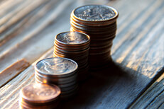 Increasing stacks of pennies, nickels, dimes, and quarters like chart in morning light