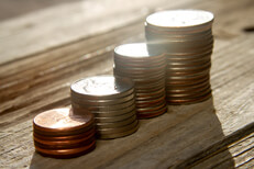 Increasing stacks of pennies, nickels, dimes, and quarters like chart with sun flare