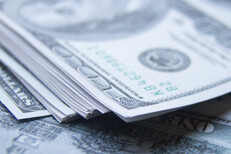 Large, messy stack of $100 bills on top of scattered $100 bills