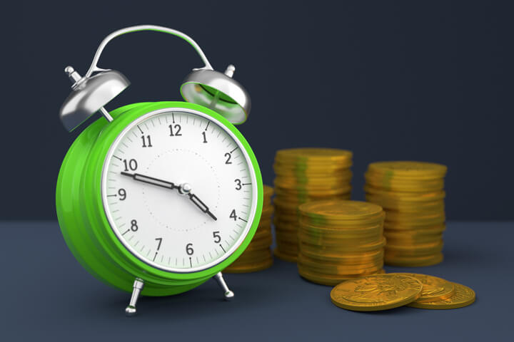 Concept image with clock and stacks of gold coins for savings, time value of money, or compound interest