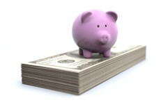 Pink piggy bank on stack of bills concept for retirement, investment, or savings account
