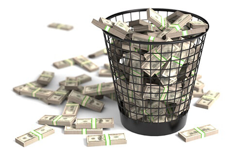 Bundles of cash thrown in trash can concept for waste or mismanagement of funds