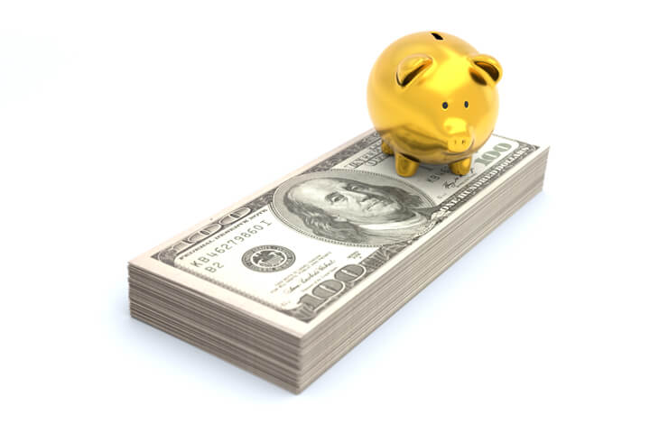 Gold piggy bank sitting on stack of Benjamins representing wealth, savings, investment, or retirement