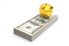 Gold piggy bank sitting on stack of Benjamins representing wealth, savings, investment, or retirement