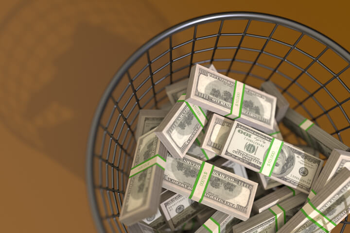 Trash can filled with money concept for waste or throwing money away view from top