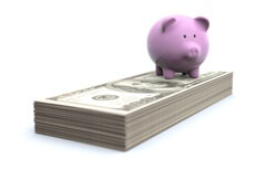 Concept photo of pink piggy bank standing on top of stack of U.S. 100 dollar bills