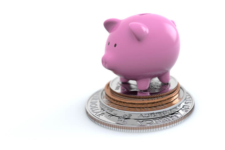 Pink piggy bank standing on stack of U.S. coins