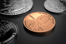 Penny, nickel, dime, and quarter on dark background