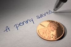 U.S. penny on paper with pen writing A penny saved