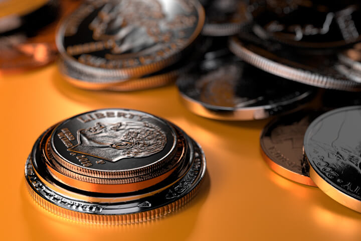U.S. coins stacked in foreground with random pile of coins on orange background