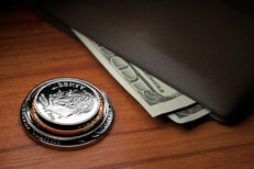 Stack of U.S. coins with wallet and protruding bills on wood table