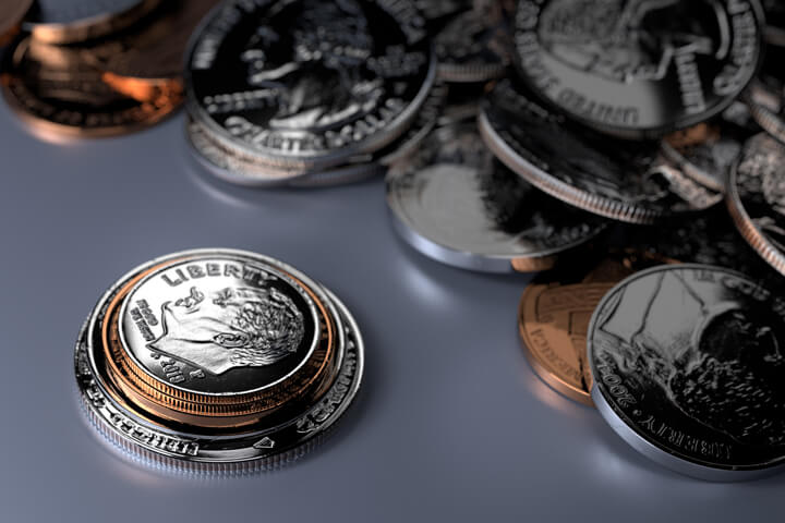 U.S. coins stacked in foreground with random pile of coins on blue background