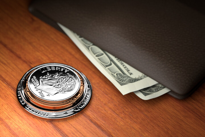 U.S. coins stacked on wood table with wallet with protruding bills harder spotlight