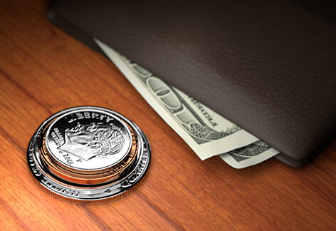 U.S. coins stacked on wood table with wallet with protruding bills harder spotlight