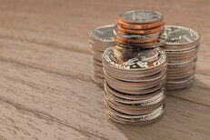 Three large stacks of shiny quarters with other smaller coins on top