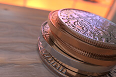 Stack of U.S. coins on wood at angle with sunlight in window in the background