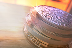 Stack of U.S. coins with light flare on wood at angle with sunlight in window in the background
