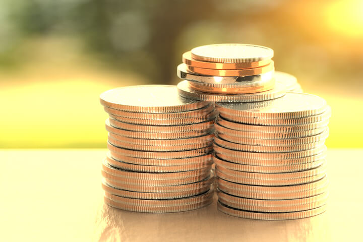 Large stacks of U.S. coins on wood table with sunny yard in background outside window with nice overlay effect