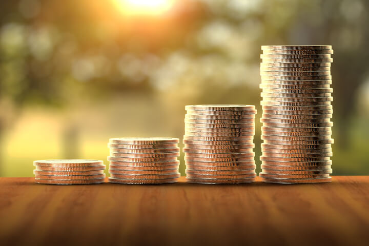 Stacks of coins in front of sunny window increasing like a bar chart to show investment returns over time