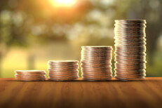 Stacks of coins in front of sunny window increasing like a bar chart to show investment returns over time