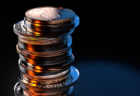 Large stack of U.S. coins offcenter left lit with orange and blue lighting on dark background