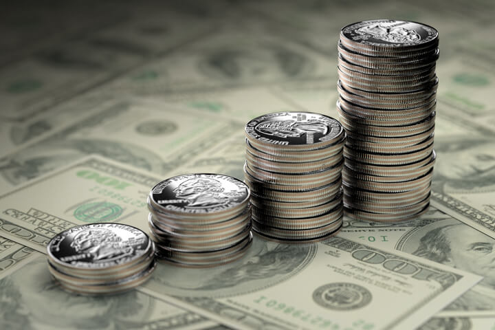 Increasing stacks of U.S. quarters stacked on one hundred dollar bills