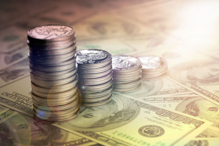 U.S. quarters stacked from large to small on top of one hundred dollar bills with lens flare and overlay