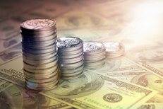 U.S. quarters stacked from large to small on top of one hundred dollar bills with lens flare and overlay