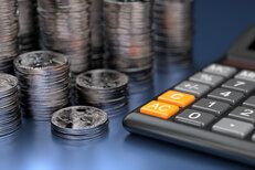 Calculator in foreground with large stacks of U.S. quarters in background on blue reflective surface