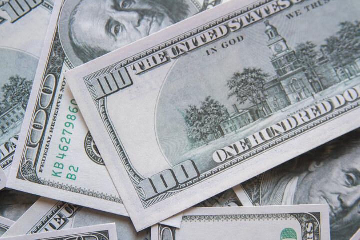 Top view of scattered $100 bills showing fronts and backs