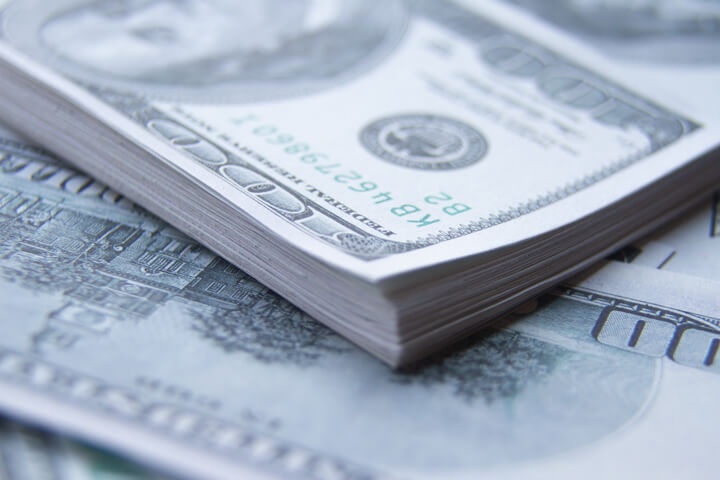 Orderly stack of $100 bills on top of other scattered $100 bills