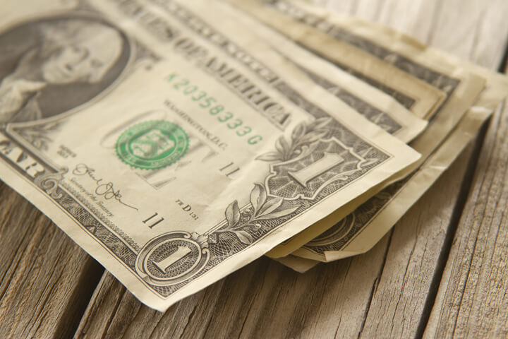 Angled view of random stack of dollar bills on wood plank background