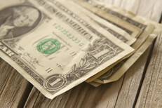 Angled view of random stack of dollar bills on wood plank background