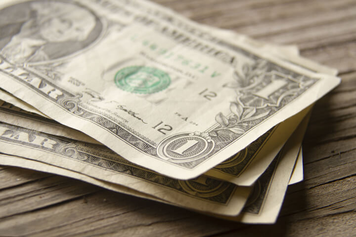 Angled view of random stack of dollar bills on wood plank background
