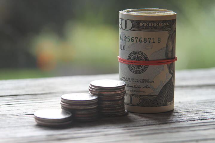 Increasing stacks of quarter coins with roll of bills as last column