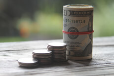 Increasing stacks of quarter coins with roll of bills as last column