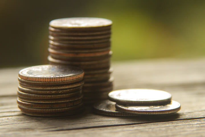 Coins stacked on wood planks with nature bokeh background