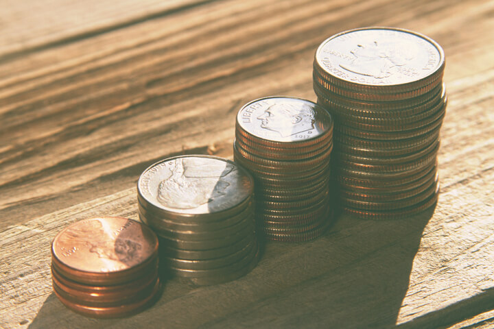 Stacks of pennies, nickels, dimes, and quarters on wood planks with soft vintage filter