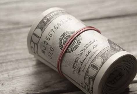 Large roll of twenty dollar bills on wood background