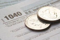 Two shiny U.S. quarters on IRS tax form 1040 concept for tax budget or paying income taxes
