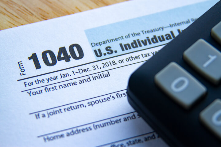 Photo showing 1040 IRS tax form and corner of calculator on desk