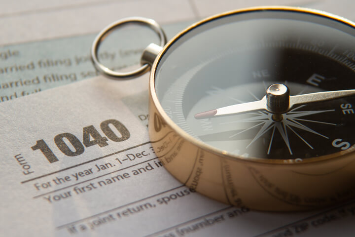 Concept image of 1040 tax form and navigation compass illustrating tax help or advice