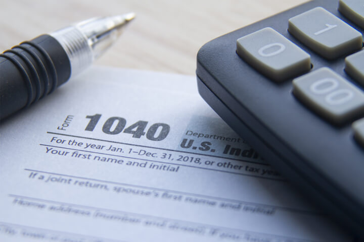 Close up photo of IRS form 1040 with calculator and ballpoint pen on desk
