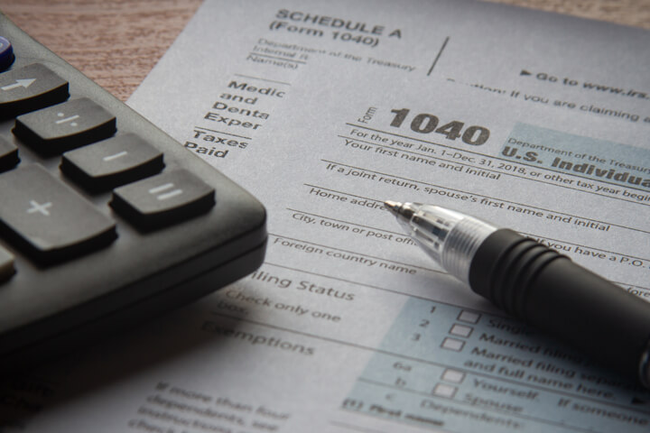 Calculator and ballpoint pen on IRS form 1040 paperwork