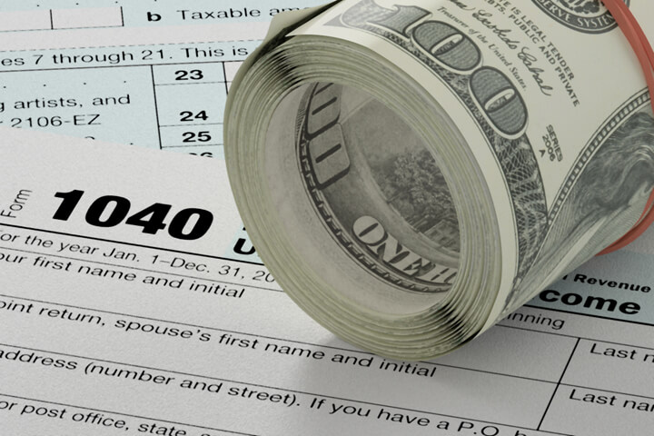 IRS form 1040 with roll of cash angled with rubber band