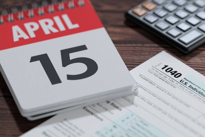 Day calendar showing April 15th with IRS tax form 1040 and calculator