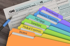 Rainbow tax category folders fanned out on top of IRS form 1040 with ballpoint pen