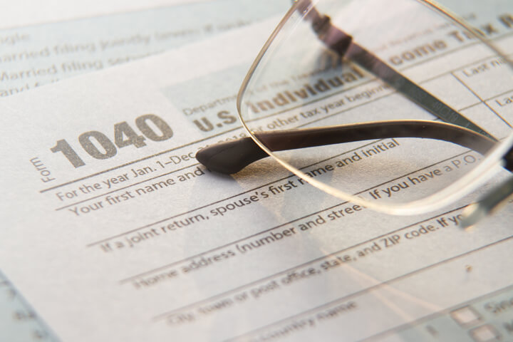 Reading glasses on IRS form 1040 paperwork with window light