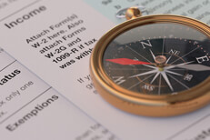 Income tax navigation Income tax forms with navigational compass concept for tax help, direction, or advice